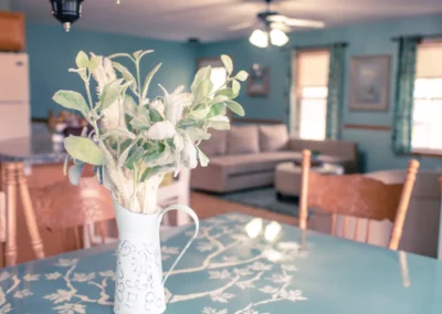 A dining table with a floral centerpiece and a living room in the background.
