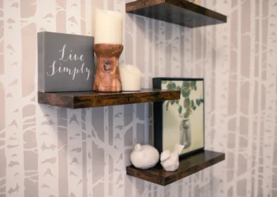 Rustic wooden floating shelves with decor against birch tree wallpaper.