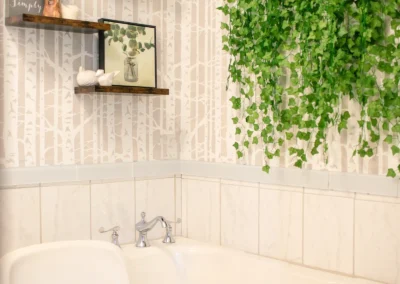 A white soaking tub with hanging greenery and wooden shelves.