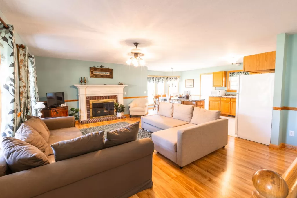 Cozy cottage living room with couch, TV, and fireplace.