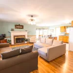 Cozy cottage living room with couch, TV, and fireplace.