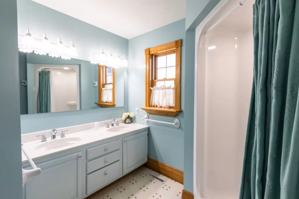 A Captain bathroom with blue walls and white counter tops.