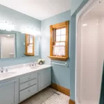 A Captain bathroom with blue walls and white counter tops.