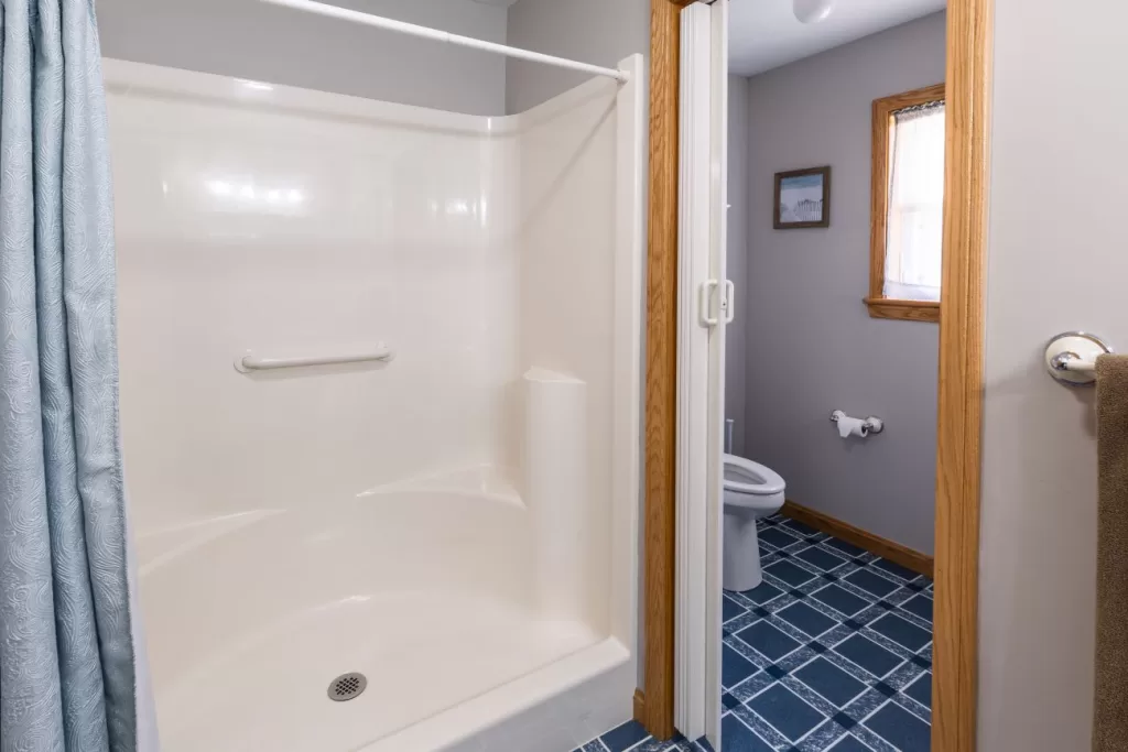 1. A cozy cottage bathroom featuring a shower and toilet, showcasing rustic charm and functional design.