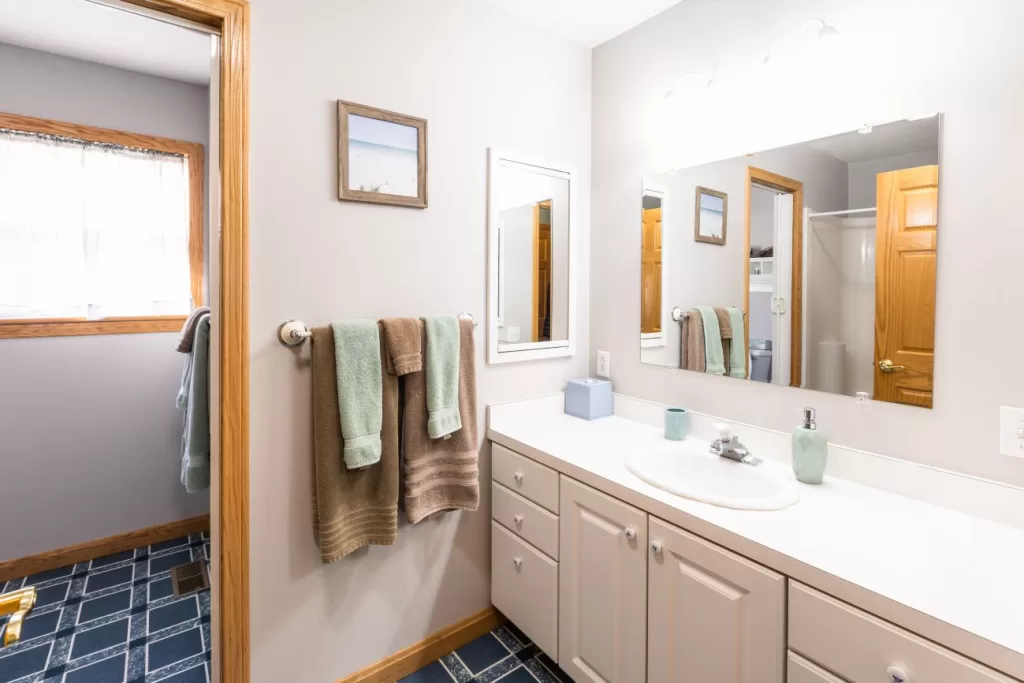 A bathroom with a sink, mirror, and towel rack.