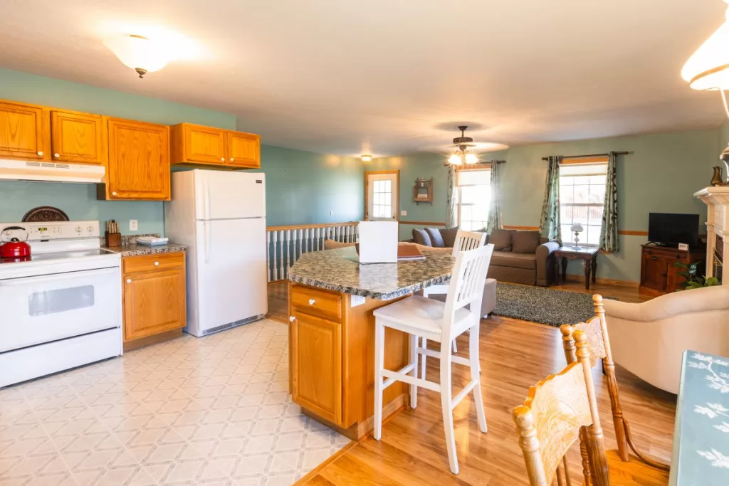 cottage kitchen and living room with a refrigerator and stove.